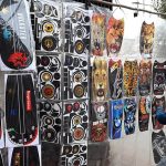 A vendor displays various plastic stickers for motorcycles along a roadside in the city