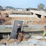 Workers are busy construction work during the extension of the Sikandari Nala Bridge on Head Muhammad Wala Road as part of an ongoing development project