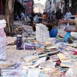 People buy old books from a roadside vendor at Saddar area